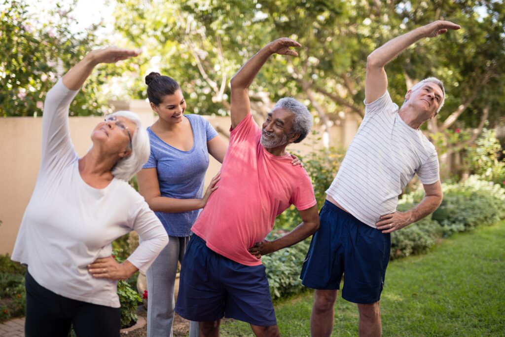 Trainer assisting senior people while exercising at park